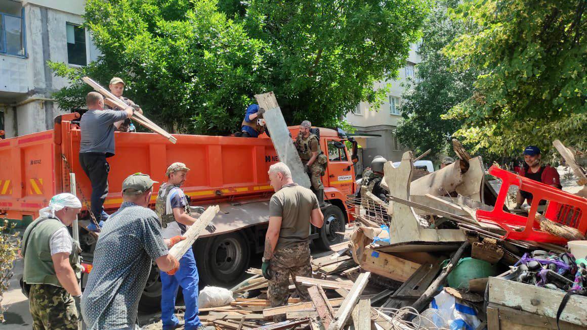 Люди загружают в машину остатки мебели и вещей, ликвидируя последствия наводнения в Херсоне