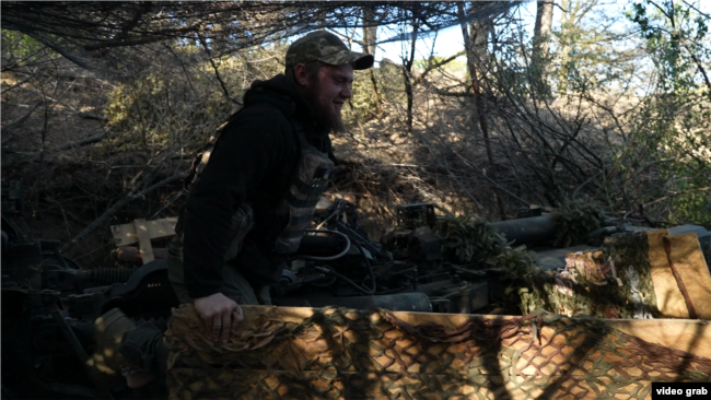 Військовослужбовець ЗСУ маскує гармату М777 у Херсонській області